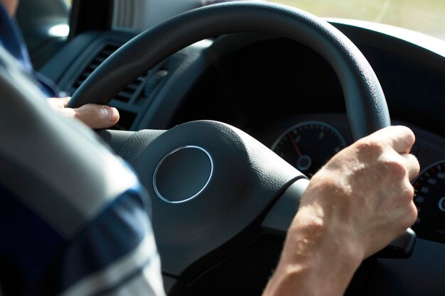 Zdjęcie mężczyzna jazdy samochodem, zbliżenie. kierowca ręce trzymając kierownicę samochodu.