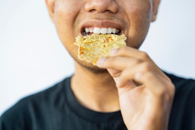 Mężczyzna je gorengan na białym tle Tradycyjne jedzenie Indonezji