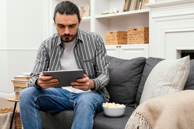 Mężczyzna je popcorn i za pomocą cyfrowego tabletu