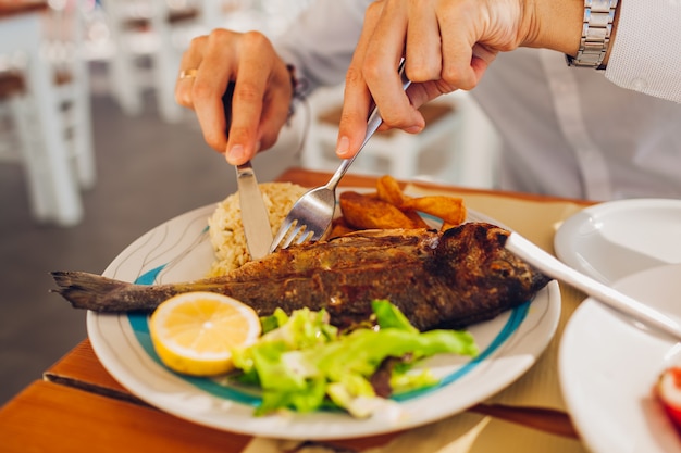 Mężczyzna je ryba z warzywami w outdoors restauraci. Świeży obiad z owocami morza podany dla jednego.