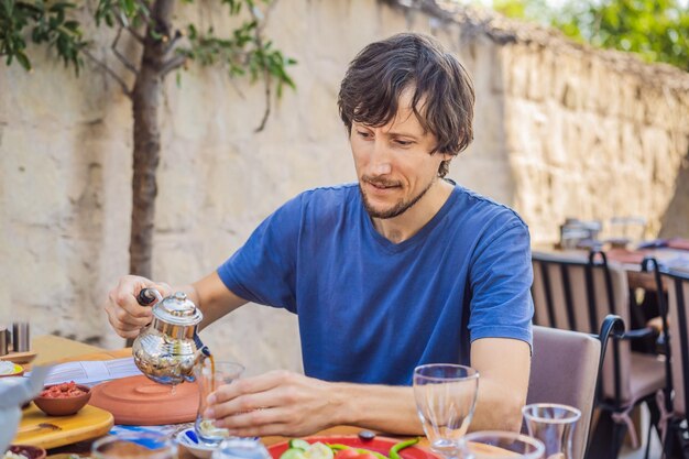 Mężczyzna jedzący tureckie śniadanie turecki stół śniadaniowy wypieki warzywa zielone oliwki sery smażone