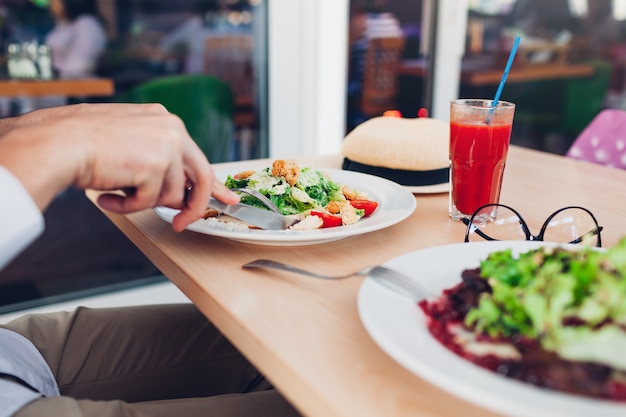 Mężczyzna jedzenie sałatka Cezar i sok pomidorowy w restauracji. Smaczny obiad. Koncepcja zdrowej żywności.