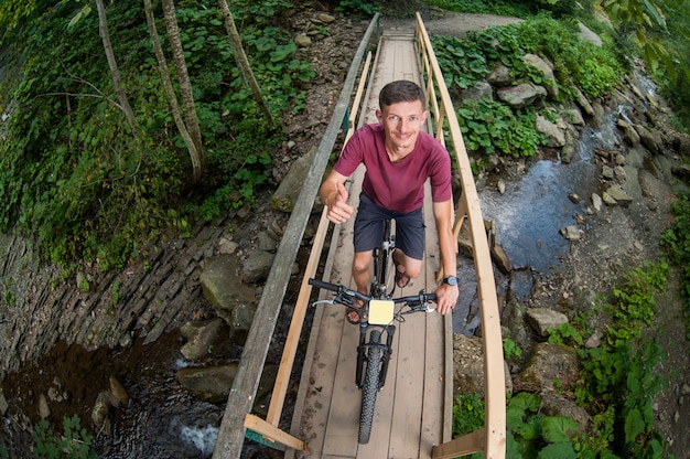 Mężczyzna jedzie na rowerze przez drewniany most nad rzeką
