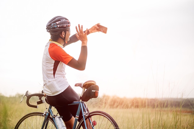 Mężczyzna jedzie na rowerze sportowym vintage na wieczorne ćwiczenia. Mężczyzna jeździ na rowerze, aby odetchnąć świeżym powietrzem pośród natury, łąki, lasu, przy wieczornym słońcu. Mężczyzna robi selfie z rowerem.