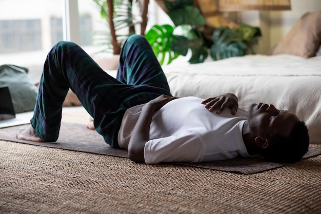 Mężczyzna jest zmęczony po treningu fitness leżąc na podłodze w domu