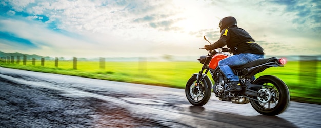 Mężczyzna jeździ motocyklem po drodze na chmurnym niebie