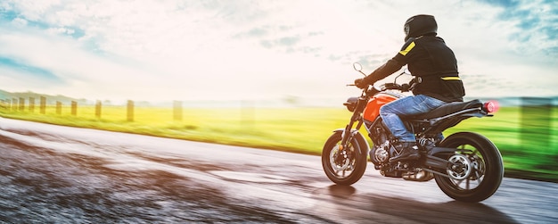 Mężczyzna jeździ na motocyklu po drodze na chmurnym niebie