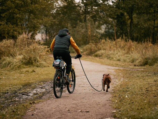 Mężczyzna jeździ na rowerze w parku ze swoim psem