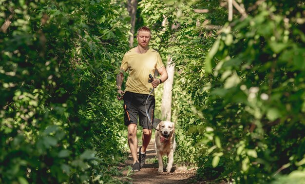 Mężczyzna jogging z psem w drewnie