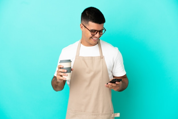 Mężczyzna Kelner W Restauracji Na Białym Tle Niebieski Trzyma Kawę Na Wynos I Telefon Komórkowy