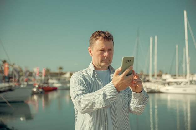 Mężczyzna komunikuje się przez telefon na tle jachtów i mariny