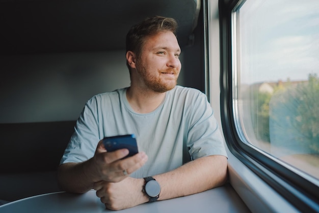 Mężczyzna korzystający ze smartfona podczas podróży pociągiem kolejowym