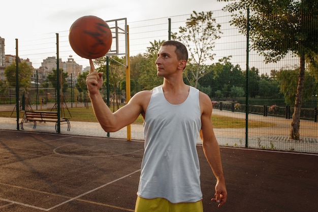 Mężczyzna koszykarz kręci piłkę na palcu na korcie