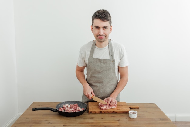 Mężczyzna kroi mięso nożem na desce do krojenia Drewniany stół Patelnia do świeżego mięsa wieprzowego