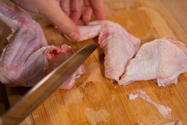 Zdjęcie mężczyzna kroi surowe skrzydełka z kurczaka, przygotowując składniki zdrowej diety