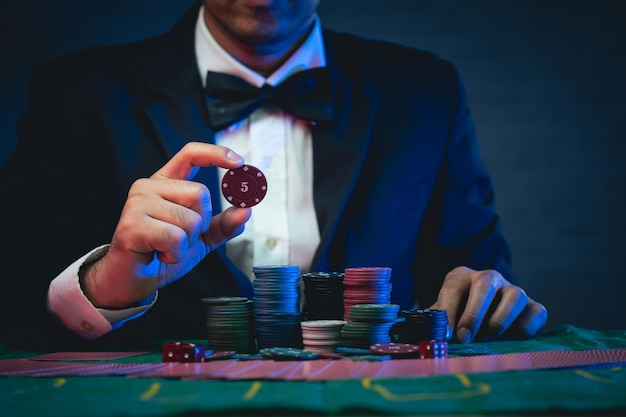 Mężczyzna Krupier Lub Krupier Tasuje Karty Pokera, Pokazuje żeton W Kasynie Asasman Trzymający Dwie Karty Do Gry Koncepcja Gry W Pokera W Pokera W Kasynie