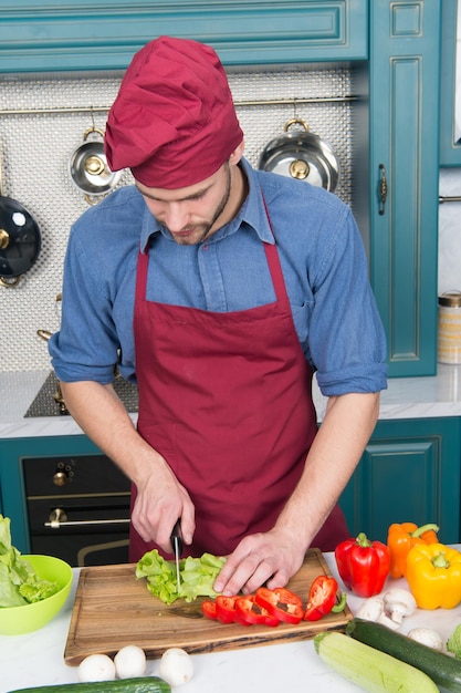 Mężczyzna kucharz gotuje jedzenie zgodnie z przepisem w kuchni restauracji Mężczyzna kucharz kroi warzywa Najlepszy przepis kulinarny od szefa kuchni Restauracja pysznej kuchni