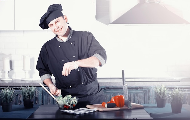 Mężczyzna kucharz przygotowuje jedzenie przy kuchennym stole z warzywami