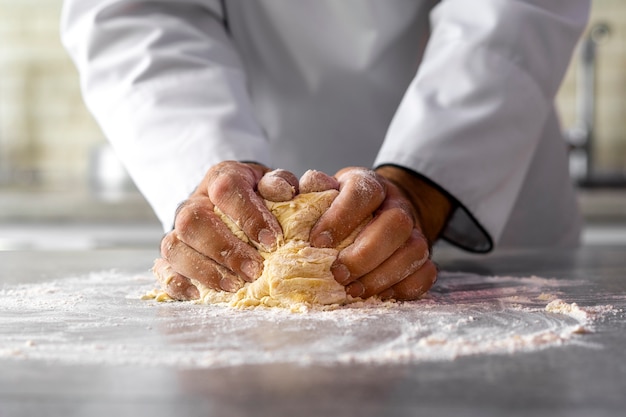 Zdjęcie mężczyzna kucharz w kuchni wyrabia ciasto