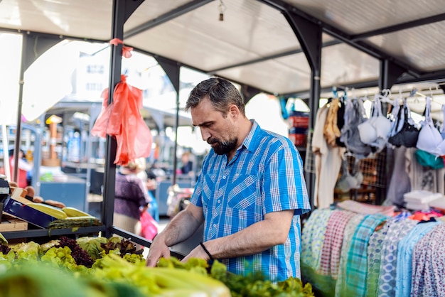 Mężczyzna kupienia warzywa Odważny brodaty mężczyzna wybiera warzywa przy marke w szkockiej kraty koszula