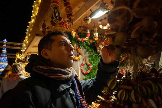 Mężczyzna kupuje prezent na jarmarku bożonarodzeniowym Podróże i wakacje zimą