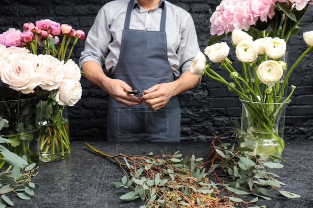 Zdjęcie mężczyzna kwiaciarnia, tworząc piękny bukiet w kwiaciarni, z bliska