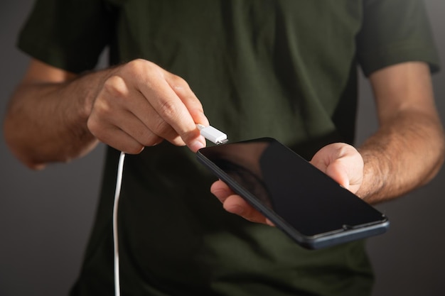 Mężczyzna łączący kabel ładowarki z telefonem komórkowym