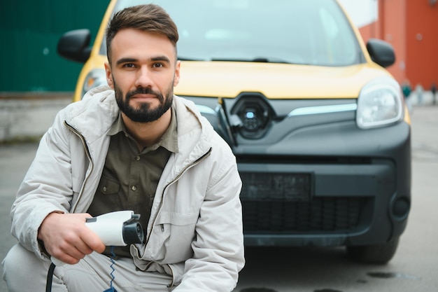 Mężczyzna ładujący samochód elektryczny przy domu