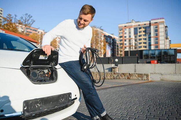 Mężczyzna ładuje samochód elektryczny na stacji ładującej