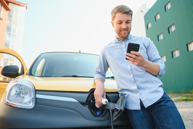 Mężczyzna ładuje samochód elektryczny na stacji ładującej