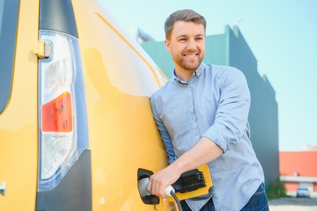 Mężczyzna ładuje samochód elektryczny na stacji ładującej