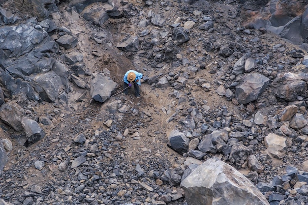 Mężczyzna łamiący skałę wulkaniczną metalowym młotkiem