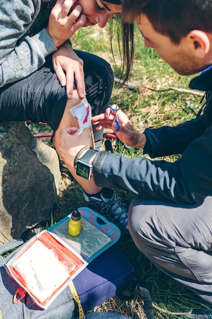 Zdjęcie mężczyzna leczący kolano kobiecie, która została ranna podczas trekkingu