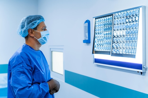 Mężczyzna lekarz bada obraz MRI ludzkiej głowy w szpitalu Oświetlona tablica z filmem rentgenowskim Lekarz w zaroślach