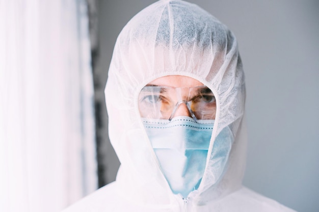 Mężczyzna lekarz lub naukowiec uzbrojony w kombinezon ochronny i maskę na twarz