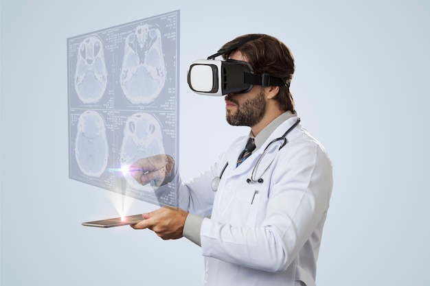 Mężczyzna lekarz na szarej ścianie patrząc na wirtualny ekran wychodzący z tabletu