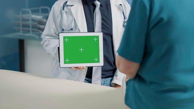 Mężczyzna lekarz posiadający poziomy zielony ekran na cyfrowym tablecie o badanie z pacjentem. Lekarz pokazujący na białym tle miejsce kopii z szablonem makiety, pustym tłem i kluczem chrominancji na wyświetlaczu.