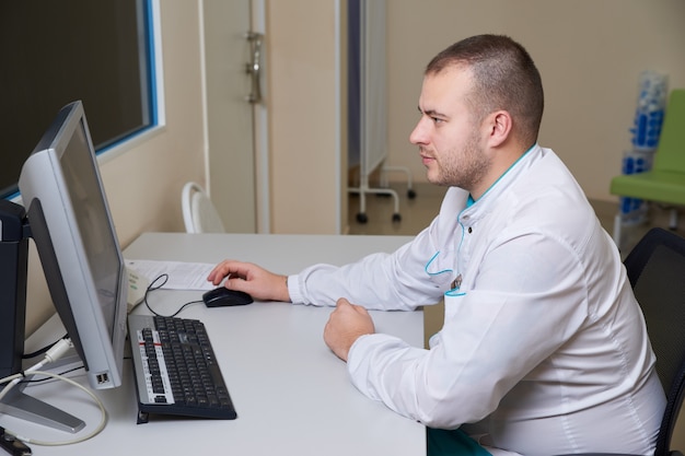 Mężczyzna lekarz pracuje na komputerze w klinice medycznej