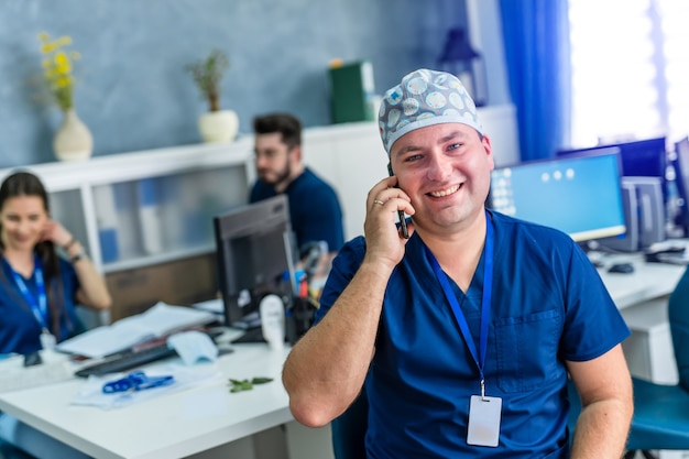 Mężczyzna lekarz w biurze uśmiecha się do kamery. Nowoczesny szpital biurowy tło.