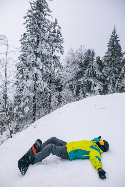 Mężczyzna leżący na śniegu z snowboardową kopią przestrzeni zimowych podróży