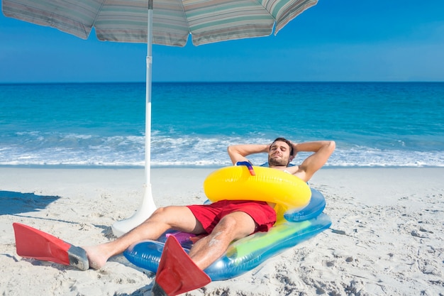 Mężczyzna leżał na plaży z ramionami i gumowym pierścieniem