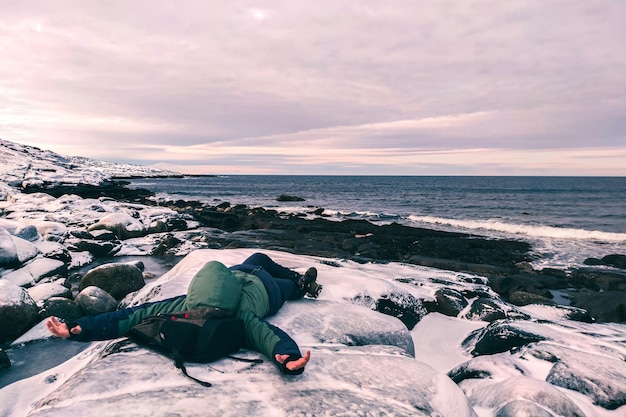 Mężczyzna leży na brzegu morza zimą w śniegu Wakacje nad Oceanem Arktycznym Zmęczony podróżnik odpoczywa