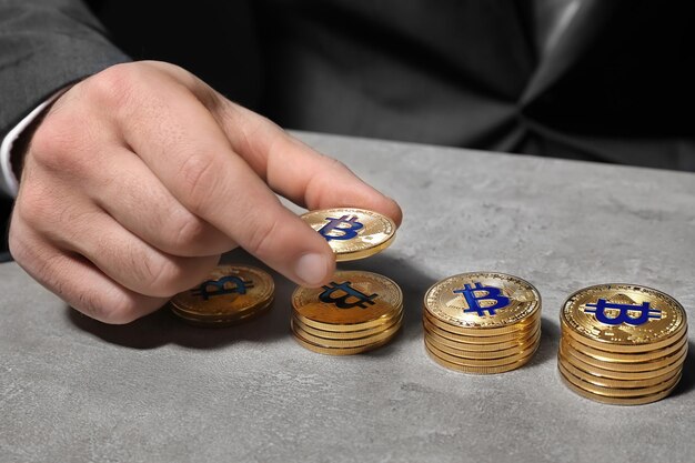 Mężczyzna liczy złote bitcoiny przy stole zbliżenie