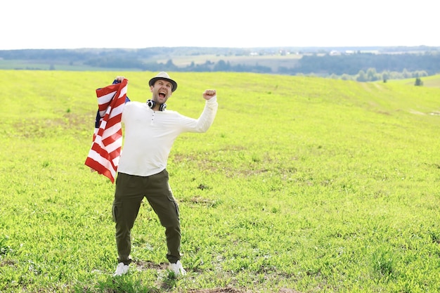 Mężczyzna machający amerykańską flagą stojący na trawie gospodarstwo rolne pole wakacje patriotyzm duma wolność partie polityczne imigrant