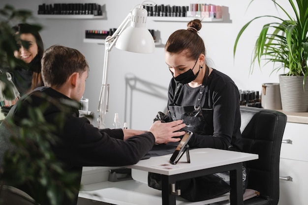 Mężczyzna manicure kobieta serwis paznokci mistrz robi manicure dla mężczyzny