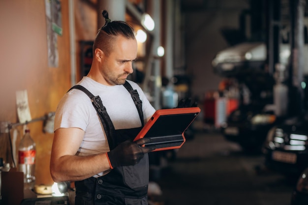 Mężczyzna mechanik z tabletem w serwisie samochodowym