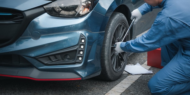 Mężczyzna mechanik zmienia koła po awarii samochodu