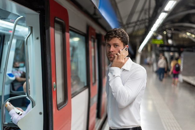 Mężczyzna menedżer mówiący na smartfonie na stacji metra