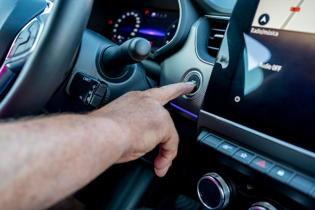 Zdjęcie mężczyzna męski palec naciskając przycisk rozruchu silnika samochodu;