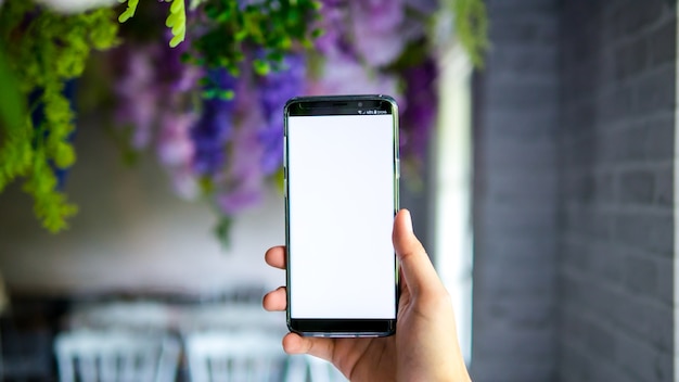 Zdjęcie mężczyzna mienia smartphone pokazu bielu ekran dla mockup app na plamy tle w decoratio